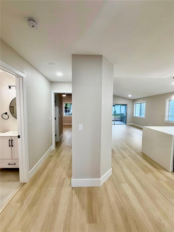 An interior view shows a hallway with light wood flooring leading toward a living area — 554 PORTLAND CIRCLE, APOPKA, FL