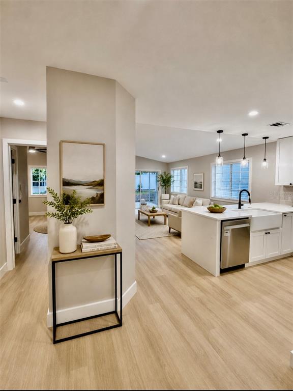 A modern kitchen with a white island and light wood flooring opens into a living area — 554 PORTLAND CIRCLE, APOPKA, FL