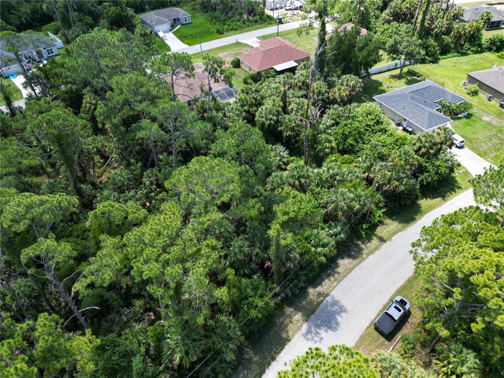 An aerial view shows a wooded residential lot situated between several houses and a road — MAYWOOD LANE, NORTH PORT, FL