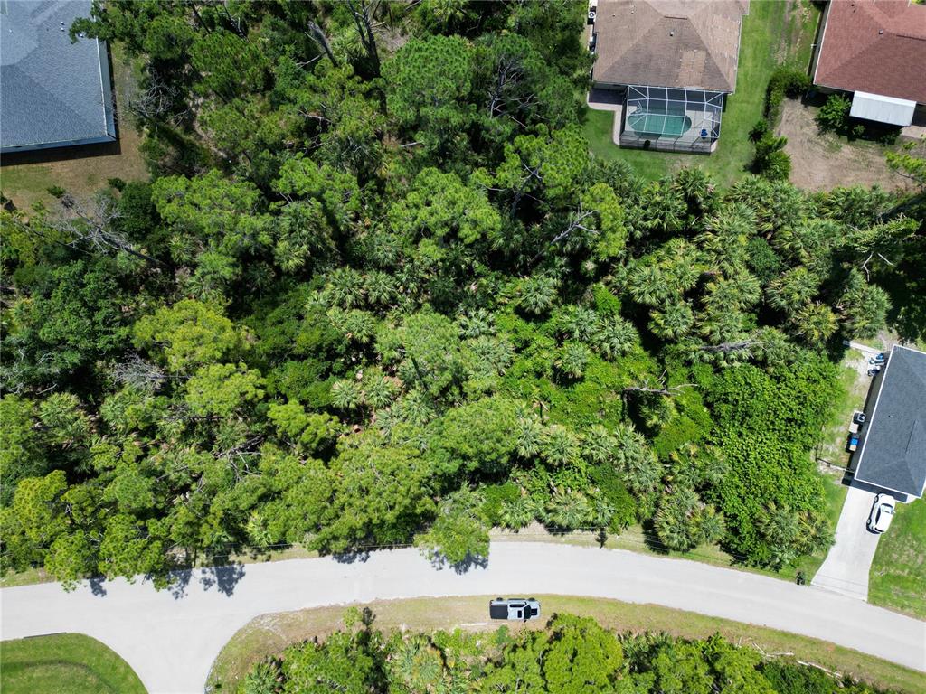 An aerial view shows a wooded residential lot situated between two houses along a road — MAYWOOD LANE, NORTH PORT, FL