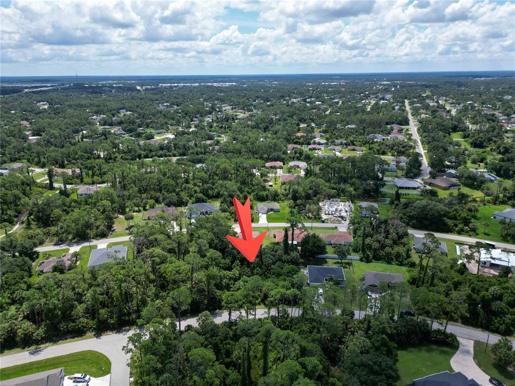 An aerial view shows a wooded, undeveloped residential lot marked by a red arrow — MAYWOOD LANE, NORTH PORT, FL