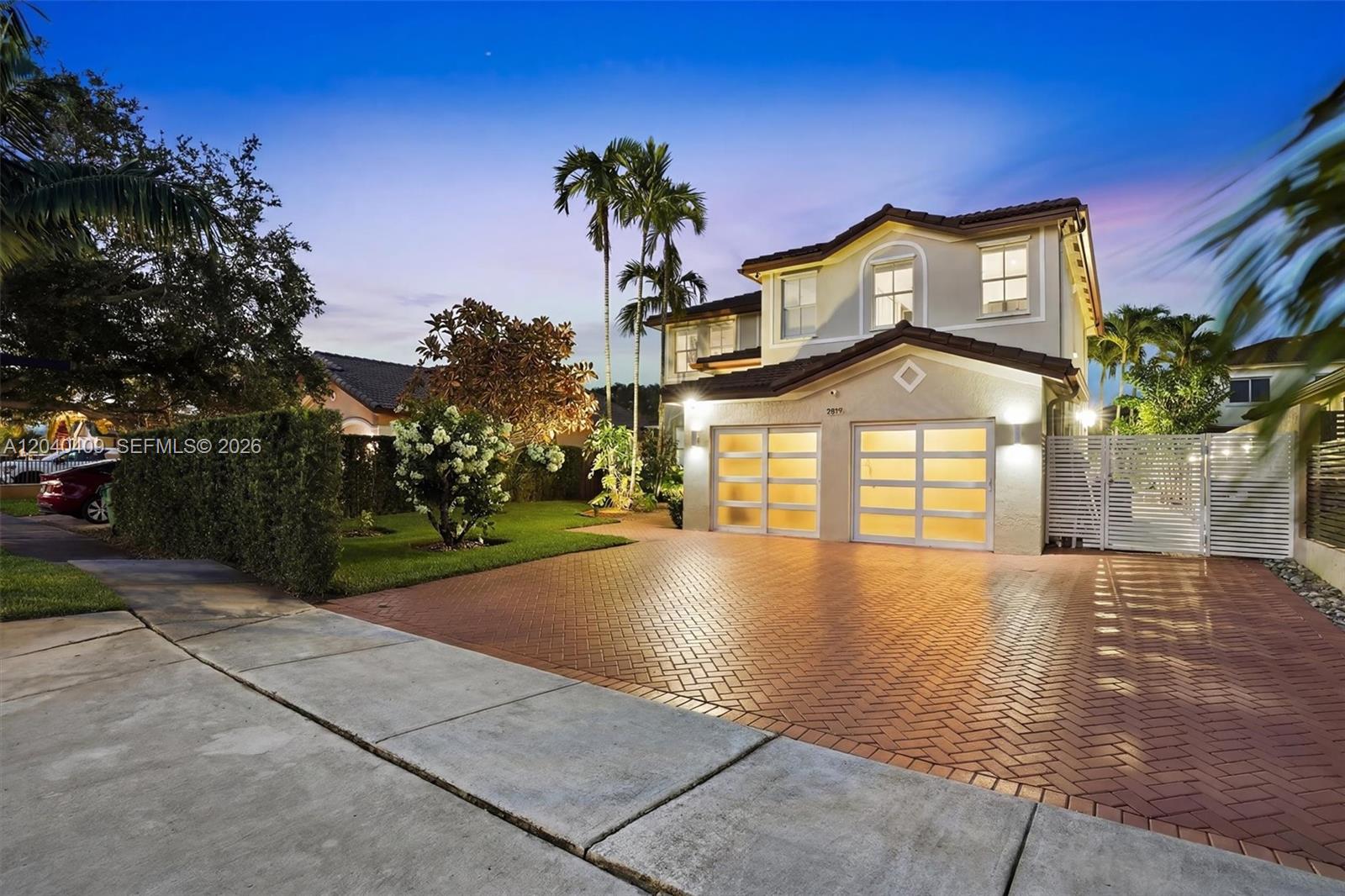 A two-story house with a brick driveway, a two-car garage, and palm trees at dusk — 2517 SW 148th Ct, Miami FL 33185, MIAMI, FL