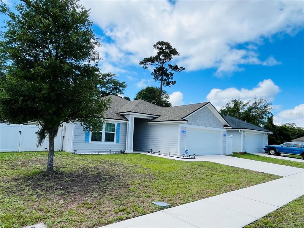 A single-story house with light blue siding, a two-car garage, and a large front tree — 6050 PATRIOTS LANDING LANE, JACKSONVILLE, FL