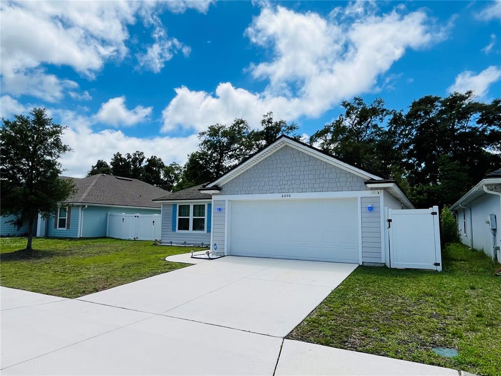 A single-story house with light gray siding, a white garage door, and a concrete driveway — 6050 PATRIOTS LANDING LANE, JACKSONVILLE, FL