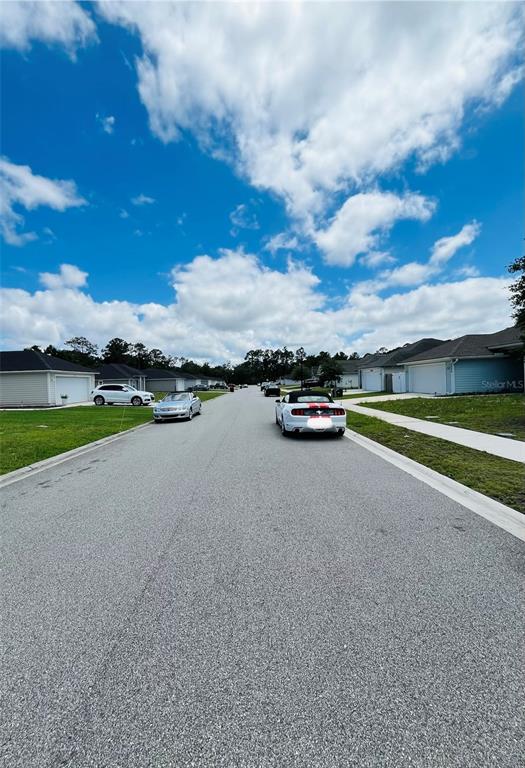 A residential street features houses on both sides with parked cars in the foreground — 6050 PATRIOTS LANDING LANE, JACKSONVILLE, FL