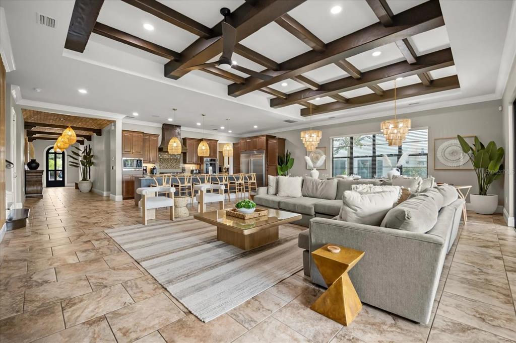 A spacious open-concept living room and kitchen featuring a coffered ceiling and tile flooring — 7846 PALMILLA COURT, REUNION, FL