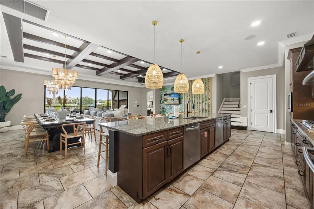 A kitchen with dark wood cabinets and granite countertops opens to a dining area — 7846 PALMILLA COURT, REUNION, FL