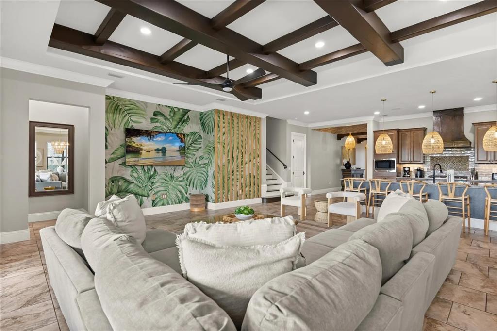 A living room with a coffered ceiling, tropical wallpaper, and a large sectional sofa — 7846 PALMILLA COURT, REUNION, FL