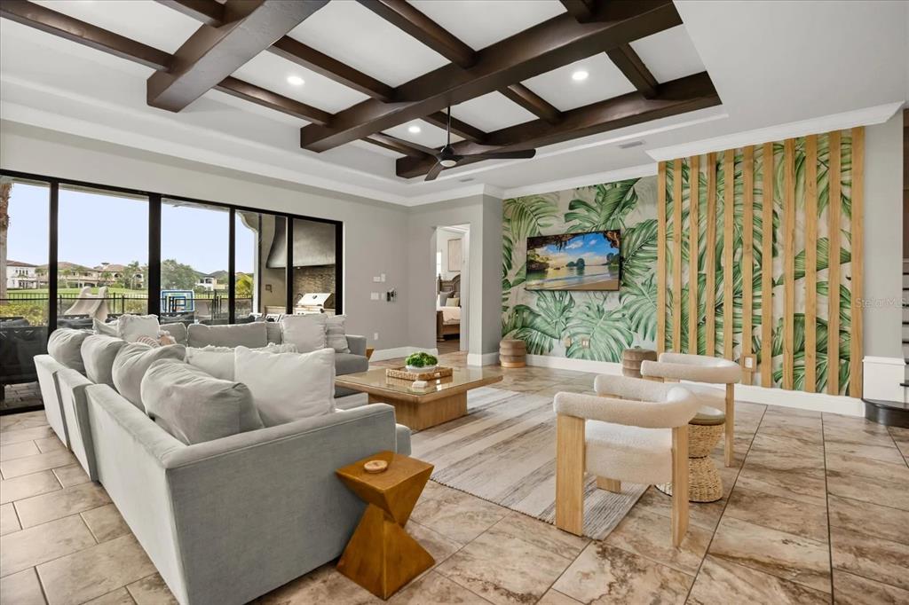 A living room with a coffered ceiling, tropical wallpaper, and a large sectional sofa — 7846 PALMILLA COURT, REUNION, FL
