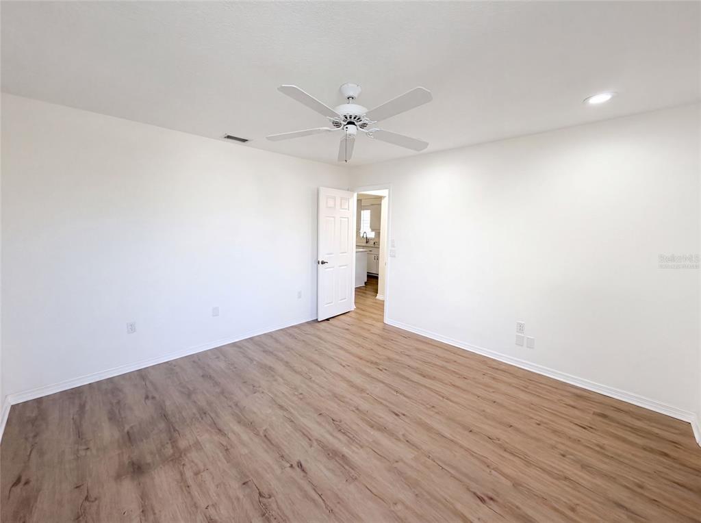 An empty room features white walls, light wood-look flooring, and a ceiling fan — 9454 MISSISSIPPI RUN, WEEKI WACHEE, FL