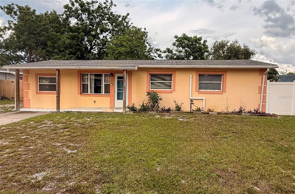 A single-story peach-colored house with a covered front porch and a grassy front yard — 880 EMERALD DR, MOUNT DORA, FL
