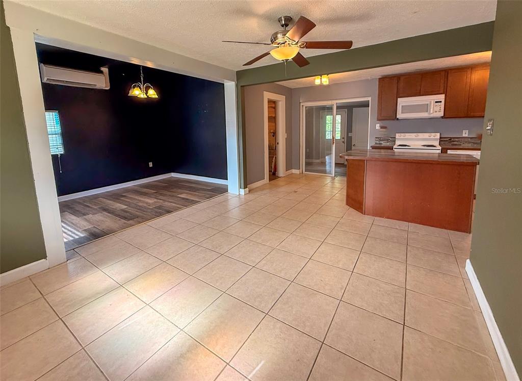 A tiled living area opens into a dark-walled dining space and a kitchen with wood cabinetry — 880 EMERALD DR, MOUNT DORA, FL