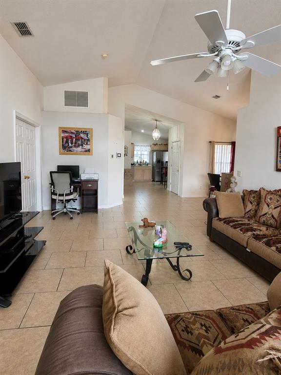 A living room with tile flooring, a glass coffee table, and a ceiling fan — 121 S ROMA WAY, KISSIMMEE, FL