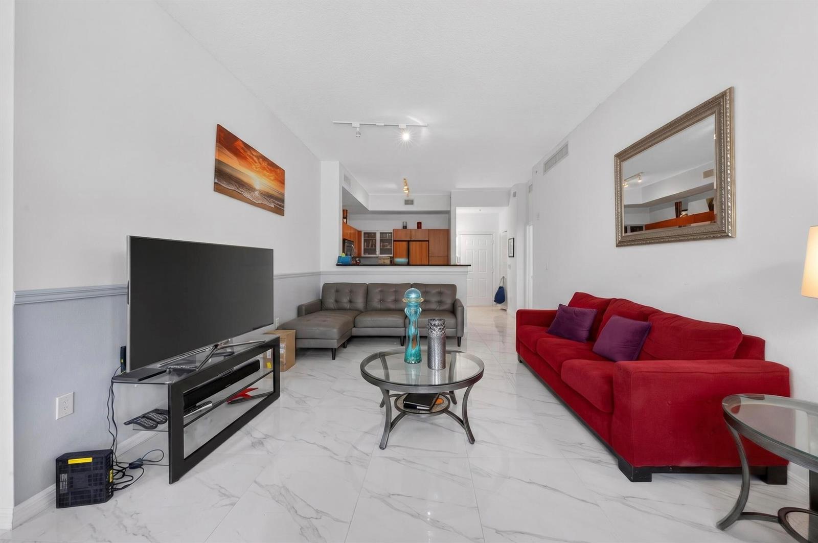 A living room features white marble-look tile floors, a red sofa, and a grey sectional — 804 E Windward Way # 111, Lantana FL 33462, LANTANA, FL