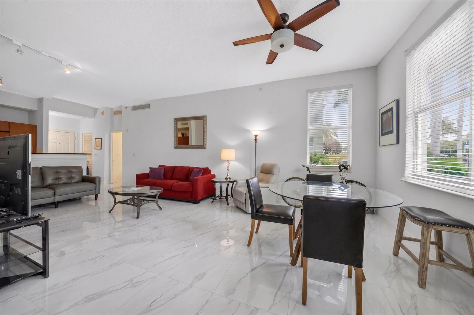 A living and dining area with white marble floors, a red sofa, and a ceiling fan — 804 E Windward Way # 111, Lantana FL 33462, LANTANA, FL