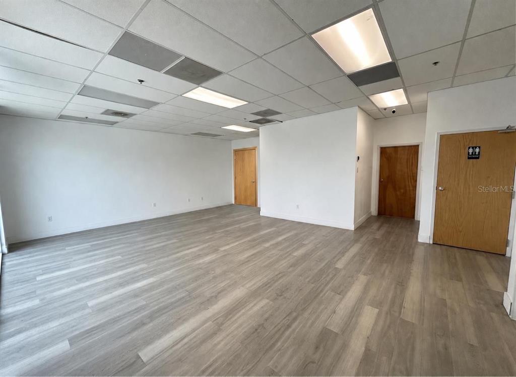 An empty office space features light wood-look flooring, white walls, and a drop ceiling — 9777 SATELLITE BOULEVARD, ORLANDO, FL