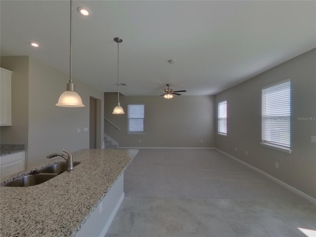 A kitchen island with granite countertops overlooks an open living area with carpeted flooring — 11611 GOLD DUST COURT, RIVERVIEW, FL