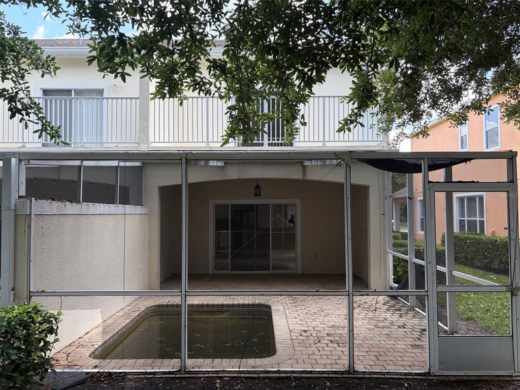 A screened-in patio features a small pool and brick pavers beneath a second-story balcony — 1407 RETREAT CIRCLE, CLERMONT, FL