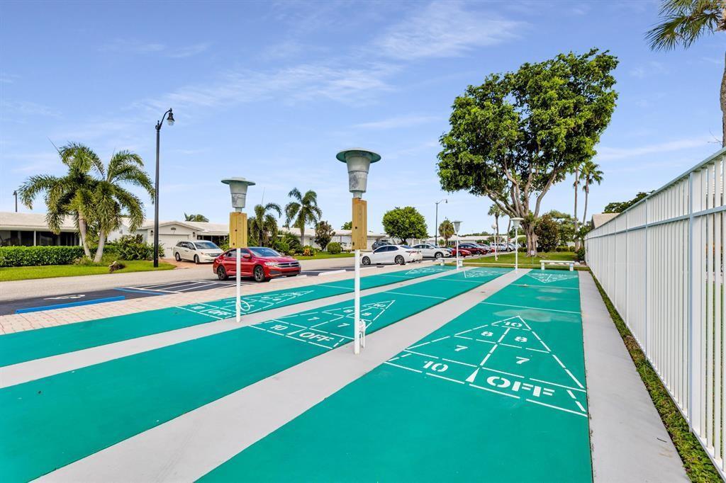 An outdoor shuffleboard court is situated next to a parking area with palm trees — 2910 E Golf Boulevard, Pompano Beach FL 33064, POMPANO BEACH, FL