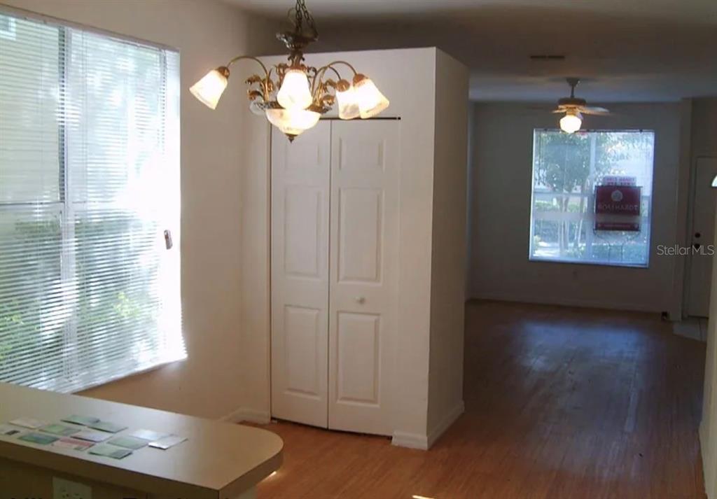A dining area with a chandelier and closet leads to a living room with wood flooring — 4415 SW 34TH STREET UNIT 708, GAINESVILLE, FL