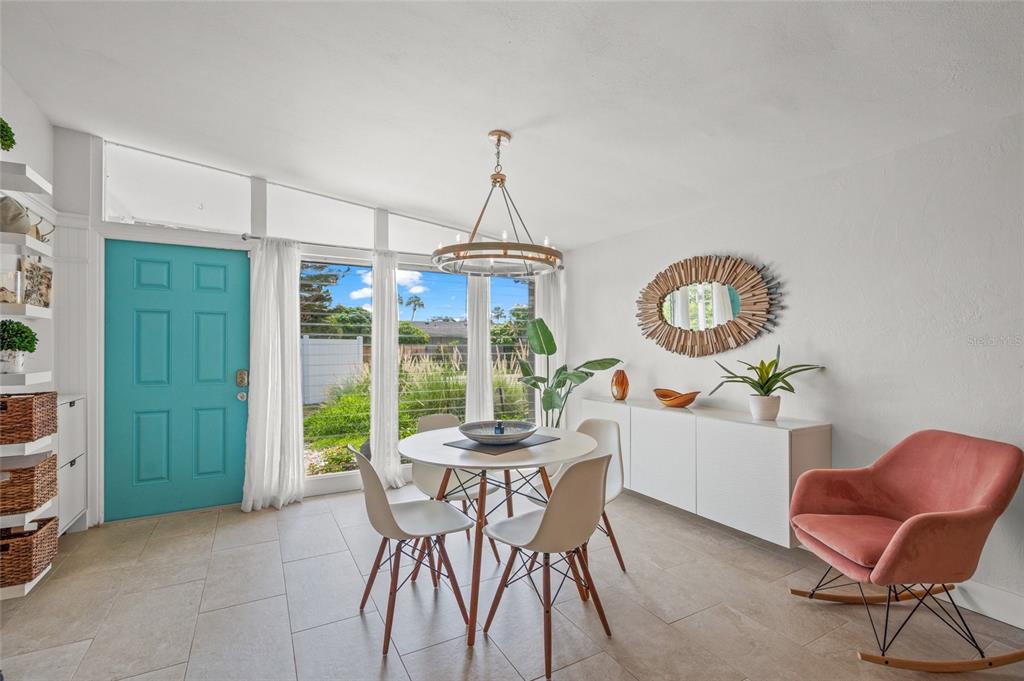 A dining room features a round table, four chairs, a pink rocking chair, and a turquoise door — 4801 SARASOTA AVENUE, SARASOTA, FL