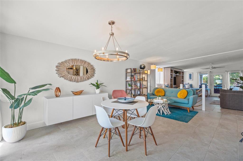 An open-concept living and dining area features a white sideboard, round table, and blue sofa — 4801 SARASOTA AVENUE, SARASOTA, FL