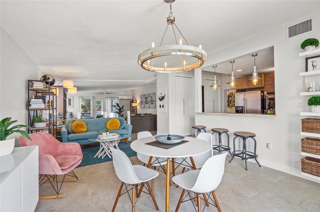 An open-concept living and dining area features a round table, blue sofa, and kitchen bar — 4801 SARASOTA AVENUE, SARASOTA, FL