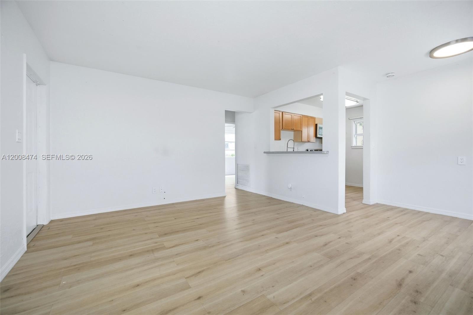 This room features light wood-look flooring, white walls, and an open pass-through to the kitchen — 2124 Taylor St, Hollywood FL 33020, HOLLYWOOD, FL