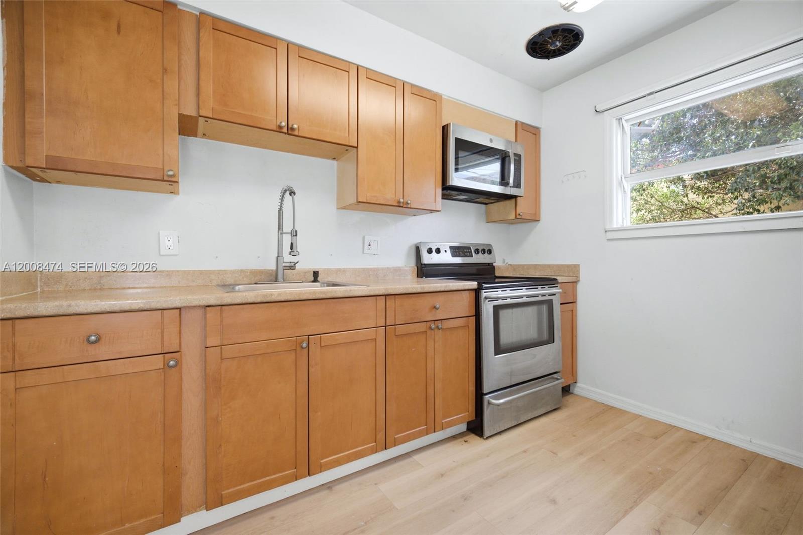 A kitchen features light wood cabinets, stainless steel appliances, and a window above the floor — 2124 Taylor St, Hollywood FL 33020, HOLLYWOOD, FL