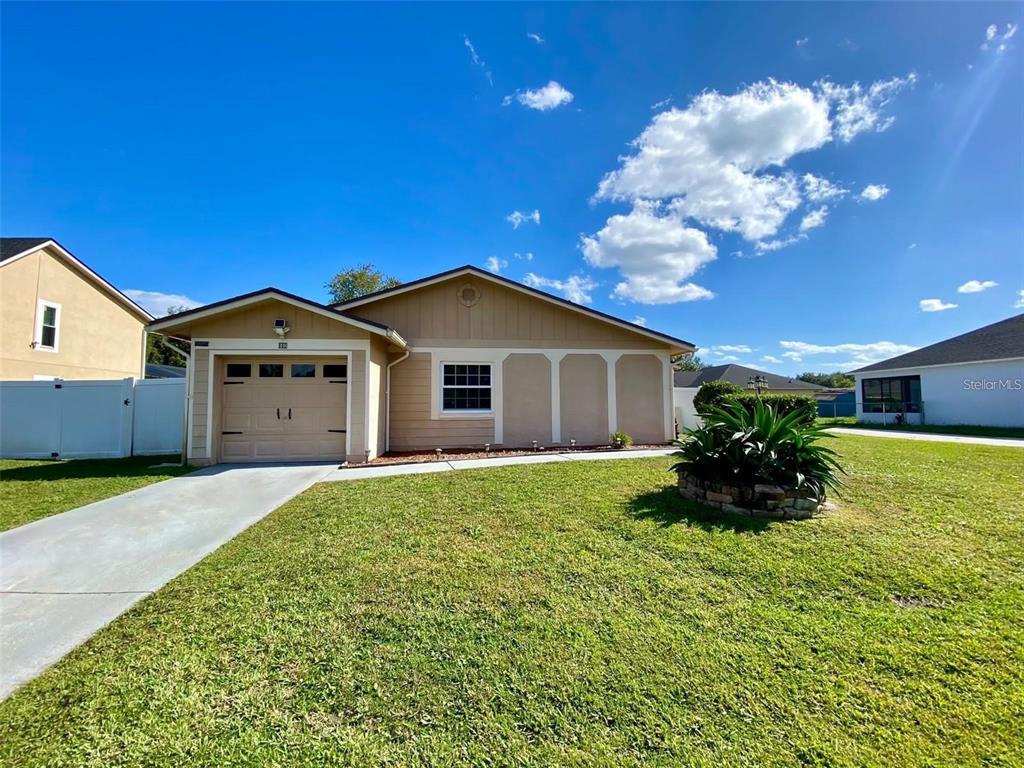 A single-story house with a tan exterior, a one-car garage, and a grassy front yard — 880 NELSON DRIVE, KISSIMMEE, FL