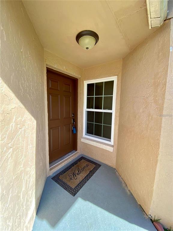 A brown front door and a window are located in a small, stucco-walled entryway — 880 NELSON DRIVE, KISSIMMEE, FL
