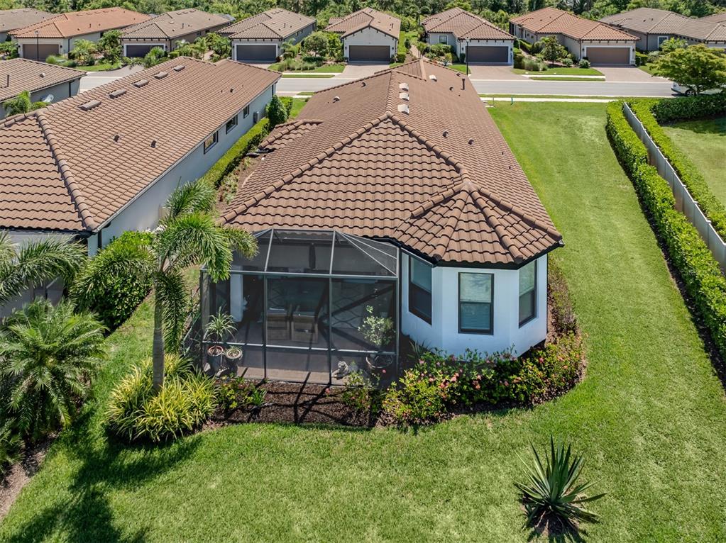 An aerial view of a house with a brown tile roof and a screened-in patio — 5853 SEMOLINO STREET, NOKOMIS, FL