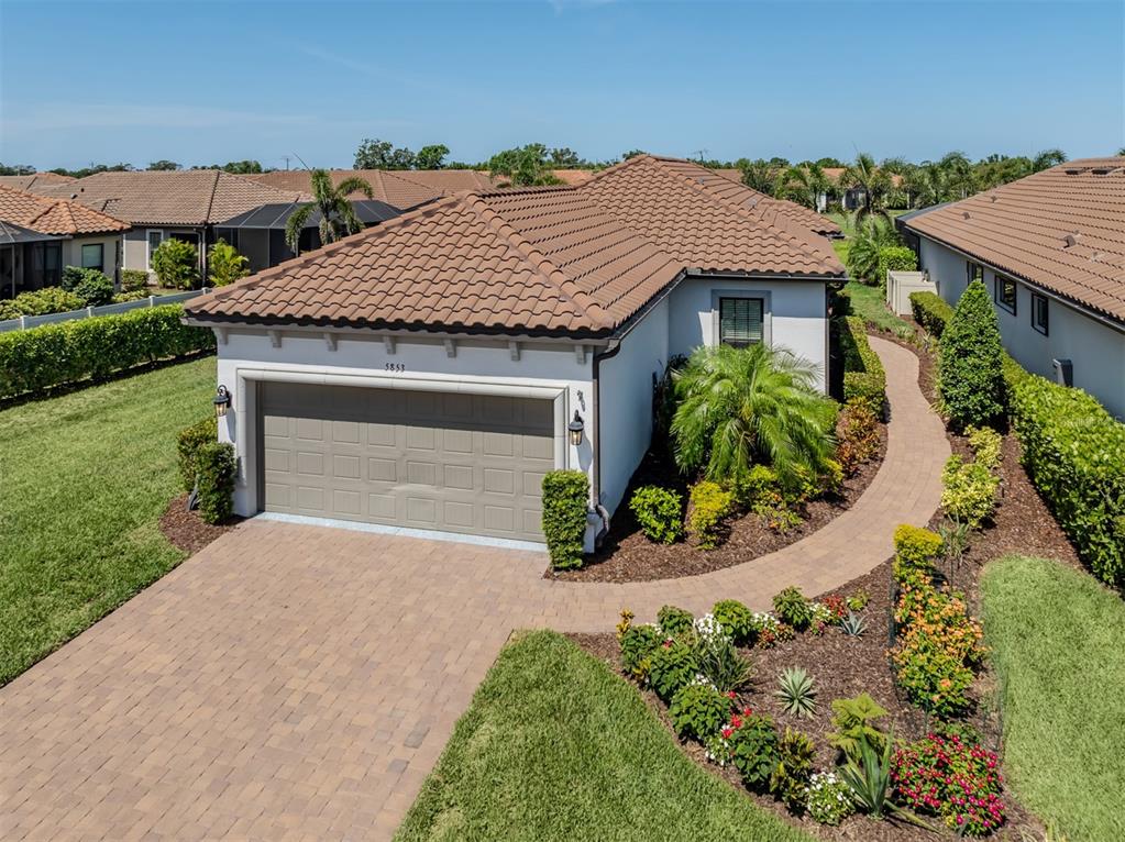 An exterior view of a single-story house featuring a tiled roof and a paved driveway — 5853 SEMOLINO STREET, NOKOMIS, FL