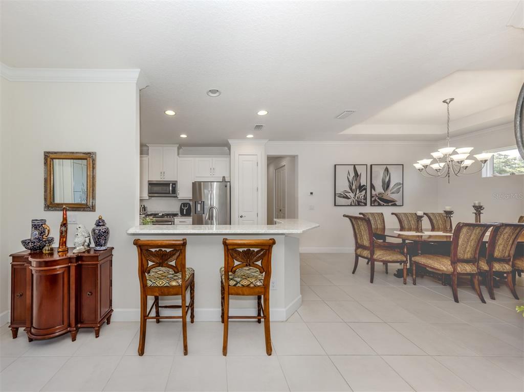 A kitchen with white cabinets and a breakfast bar overlooks a formal dining area — 5853 SEMOLINO STREET, NOKOMIS, FL