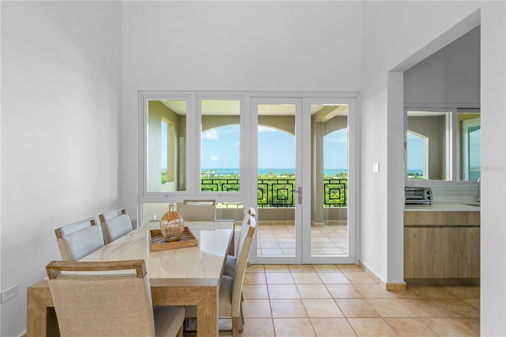 A dining area with a light-colored table, upholstered chairs, tile floors, and ocean views — 10 I UNIT 201, RIO GRANDE, PR