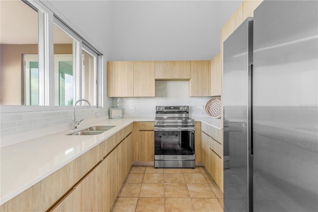 A kitchen features light wood cabinets, white countertops, stainless steel appliances, and tile flooring — 10 I UNIT 201, RIO GRANDE, PR