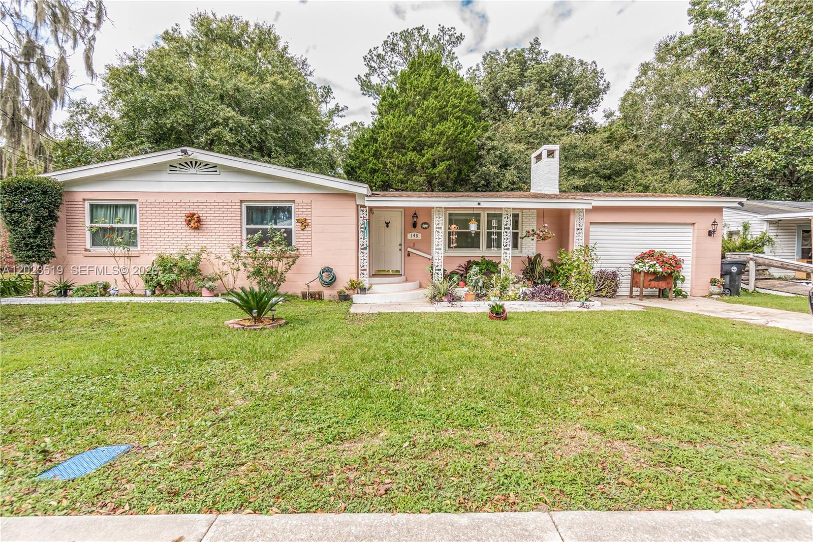 A single-story pink brick house features a white garage door and a covered front porch — 145 N ORANGE ST, Starke FL 32091, STARKE, FL