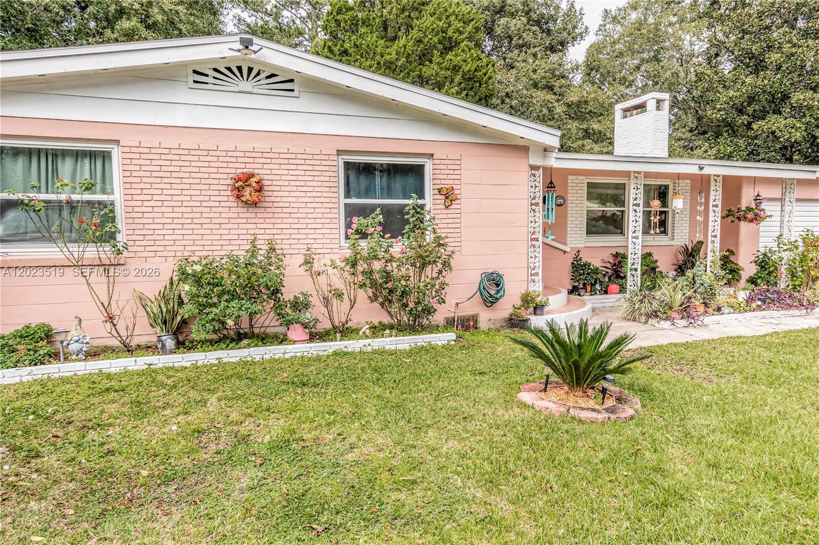 A single-story pink brick house features a white roof, a chimney, and a front porch — 145 N ORANGE ST, Starke FL 32091, STARKE, FL
