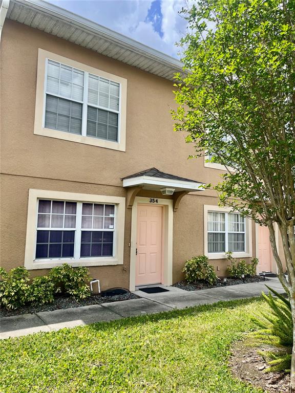 A two-story tan townhouse exterior features a light pink front door and white-framed windows — 354 CERVANTES DRIVE, KISSIMMEE, FL