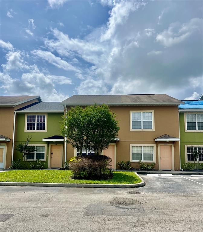 A row of two-story townhomes with tan and green siding under a cloudy sky — 354 CERVANTES DRIVE, KISSIMMEE, FL