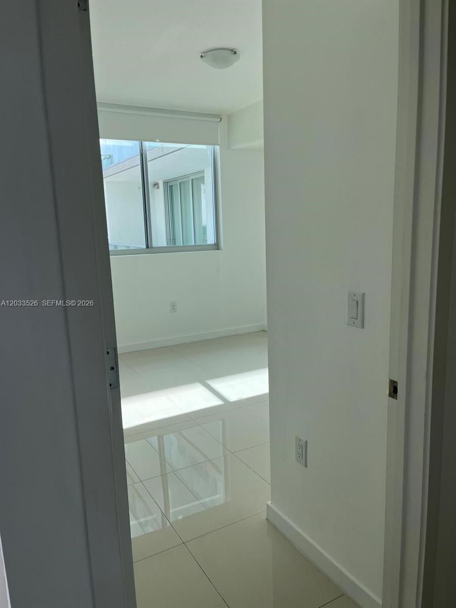 A doorway leads into a bright, empty room with white walls and light-colored tile flooring — 7825 NW 107th Ave # 506, Doral FL 33178, DORAL, FL