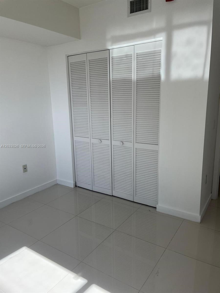 A room with white walls, light-colored tile flooring, and a four-panel louvered closet door — 7825 NW 107th Ave # 506, Doral FL 33178, DORAL, FL