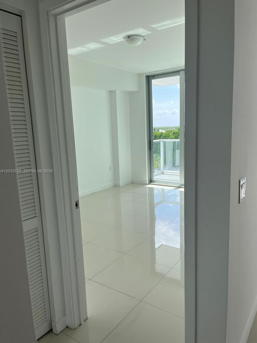 A bright, empty room with white tile floors and a sliding glass door to a balcony — 7825 NW 107th Ave # 506, Doral FL 33178, DORAL, FL