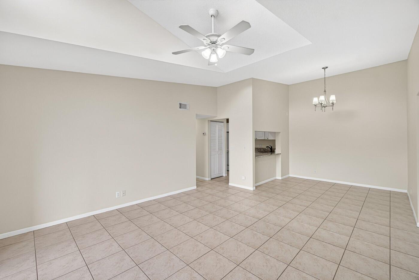 A spacious, empty room with beige tile flooring, a ceiling fan, and a chandelier — 627 Sea Pine Way # A3, FL 33415, FL