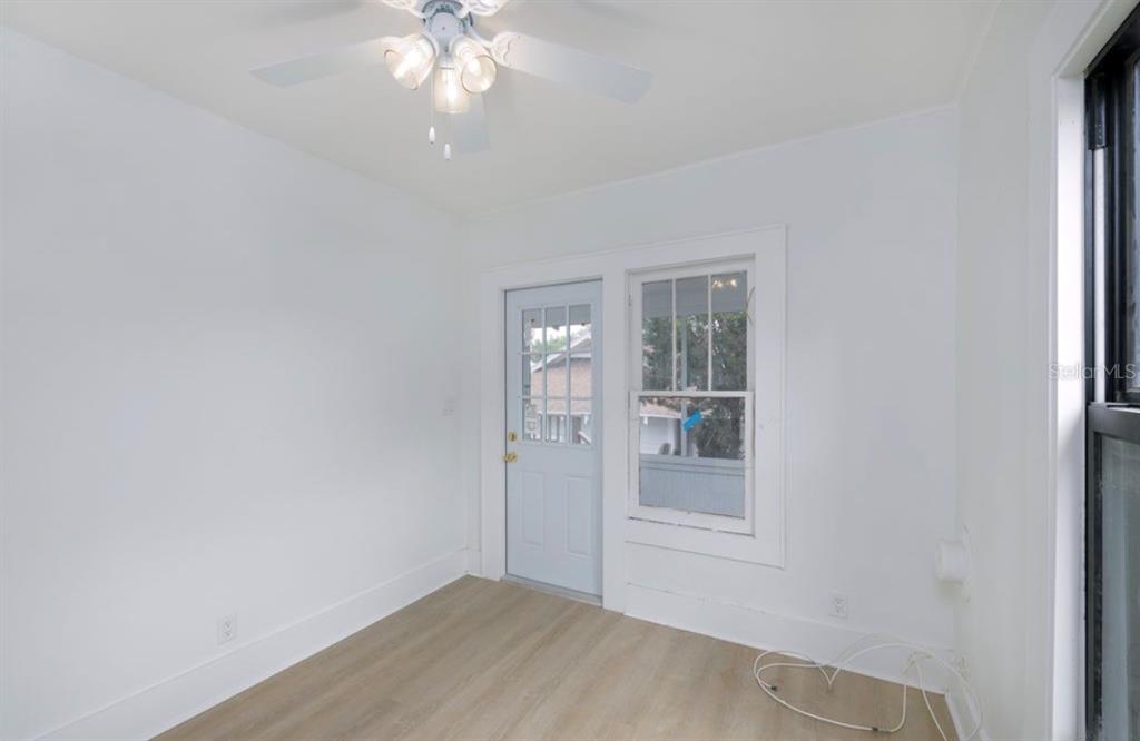 A bright room with white walls, light wood-look flooring, a ceiling fan, and a door — 622 7TH AVENUE N UNIT 618B, ST PETERSBURG, FL