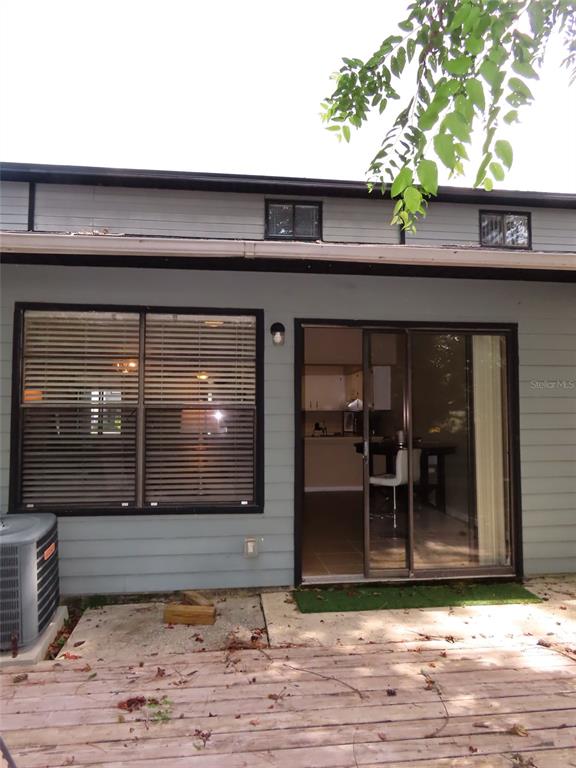A gray house exterior features a sliding glass door, a large window, and wooden decking — 4427 SW 21ST LANE, GAINESVILLE, FL