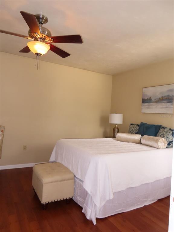 A bedroom features a bed with white bedding, a beige ottoman, and a ceiling fan — 4427 SW 21ST LANE, GAINESVILLE, FL