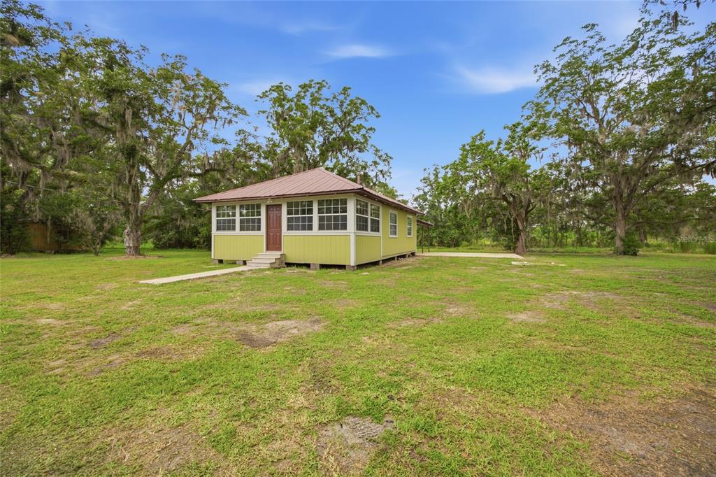 A light green, single-story house with a metal roof sits on a grassy lot — 13216 NE 140TH STREET, WALDO, FL