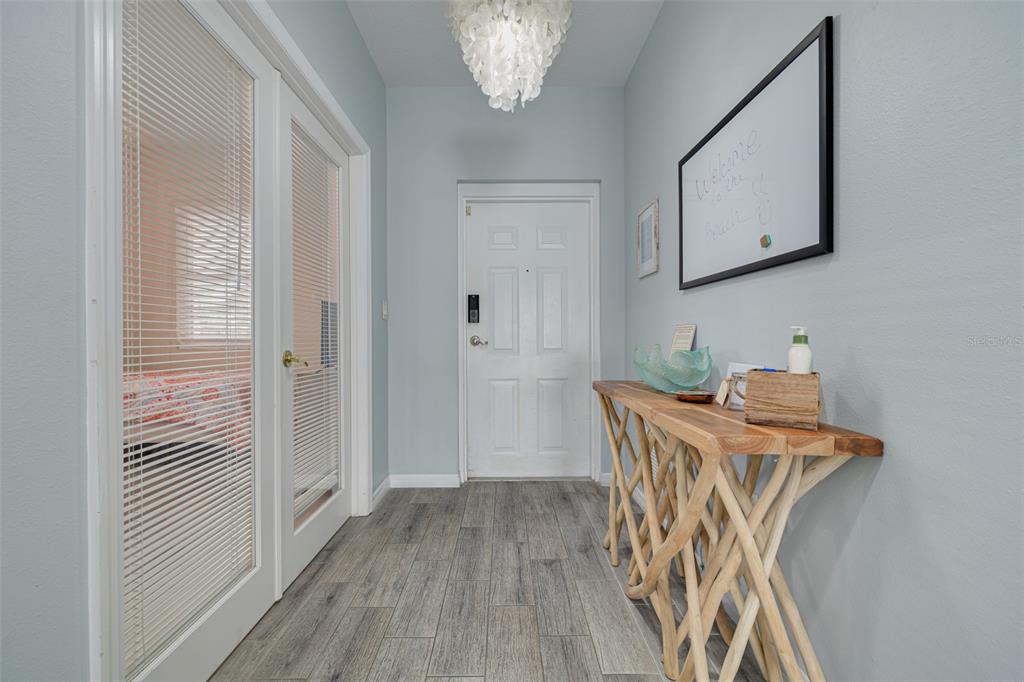 A bright entryway features light gray walls, wood-look tile flooring, and a rustic console table — 530 S GULFVIEW BOULEVARD UNIT 205, CLEARWATER, FL