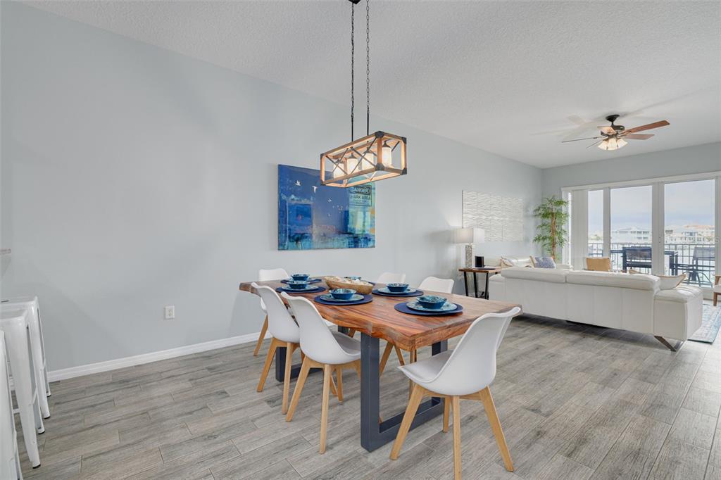 A dining area features a live-edge wood table, white chairs, and a rectangular pendant light — 530 S GULFVIEW BOULEVARD UNIT 205, CLEARWATER, FL